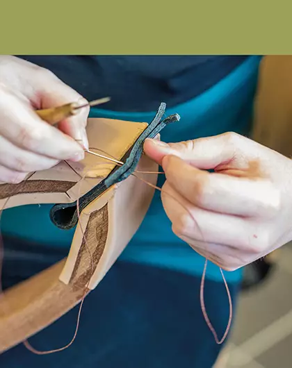 Filière Métiers d'Art et du Cuir : photo d'un artisan cousant une pièce de cuir à la main