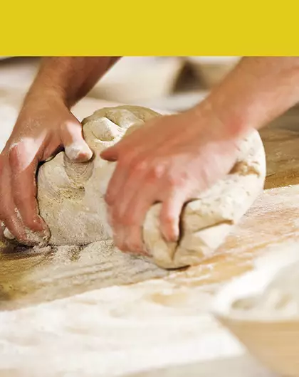 Métiers de Bouche : Photo d'un boulanger façonnant des pâtons sur un plan de travail