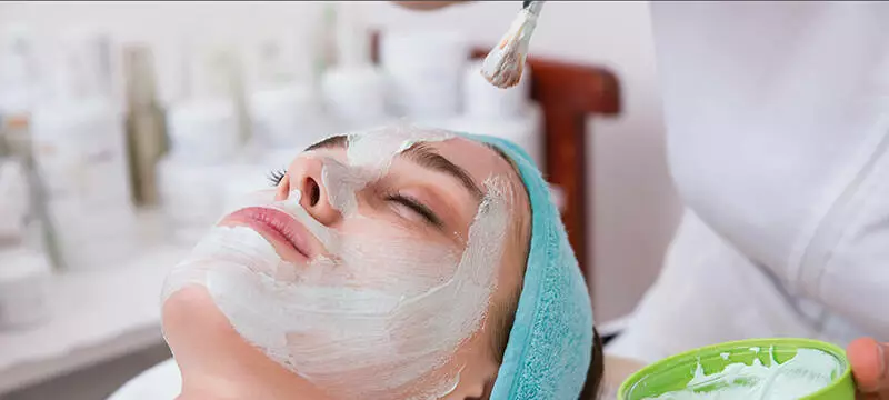 Cliente recevant un soin du visage avec un masque appliqu&eacute; sur la peau