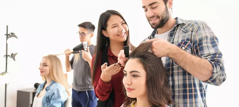 Coiffeurs r&eacute;alisant une coupe et une coiffure sur des clientes