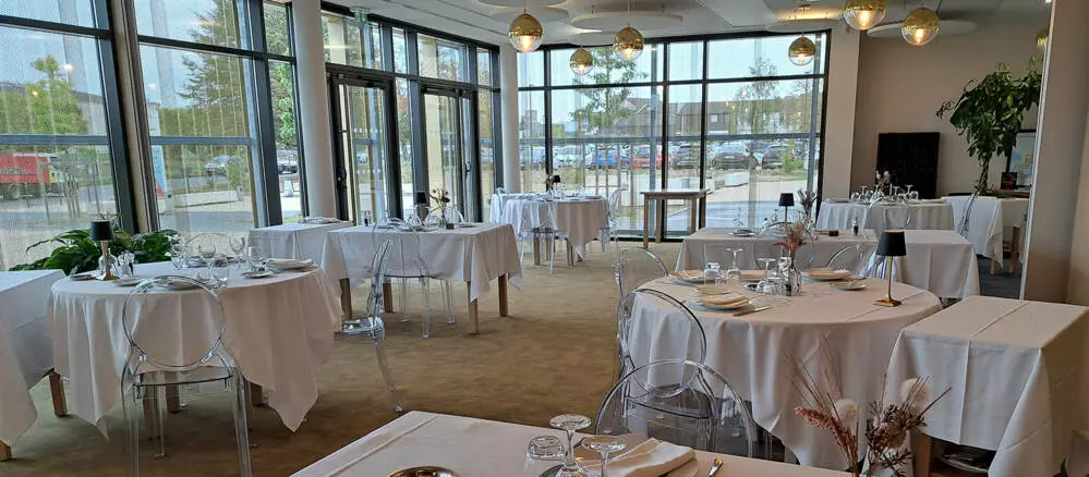 Salle de restaurant gastronomique avec tables dress&eacute;es et grandes verri&egrave;res